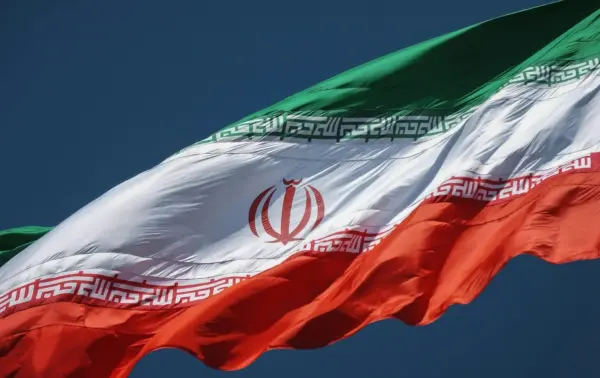 Close-up of the Iranian national flag waving in the wind, featuring green, white, and red stripes.